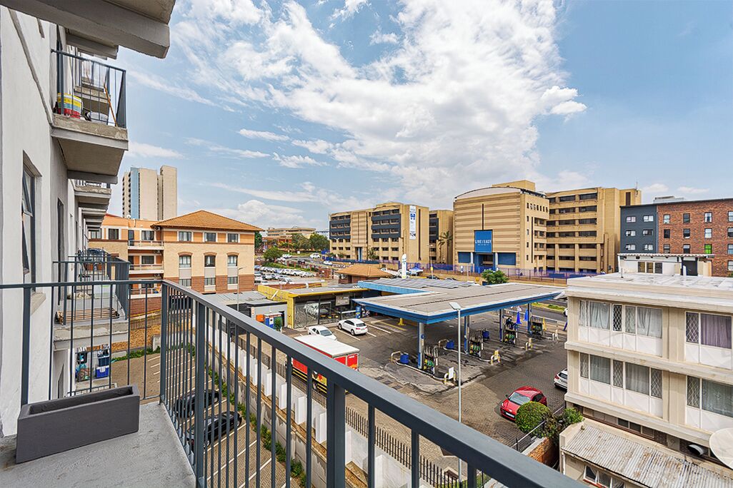 A multi-story building with balconies, a parking lot, and a gas station.