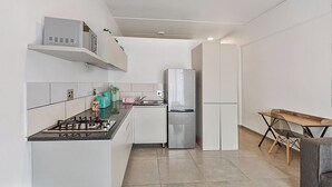 Eine moderne Küche mit weißen Schränken, einem Gasherd, einem Edelstahlkühlschrank und einem Holztisch.