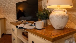 Ett mysigt rum med en tv, en lampa, en mugg och en växt på ett träbord.