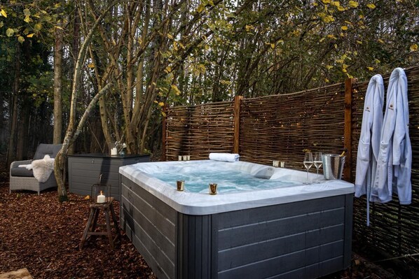 A hot tub surrounded by a wooden fence, a wicker chair, and a bench with a candle. - 1 Bed in Hanworth (oc-l43299) (Hanworth)