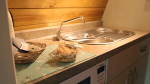 Une cuisine avec un évier en acier inoxydable, un panier de pain et un produit alimentaire emballé sur une planche à découper.