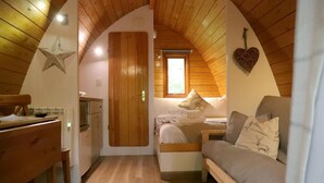 Een knus zolderkamer met houten balken, een ster decoratie, een hartvormige wandhanger, een bed met een kussen, en een houten bankje.