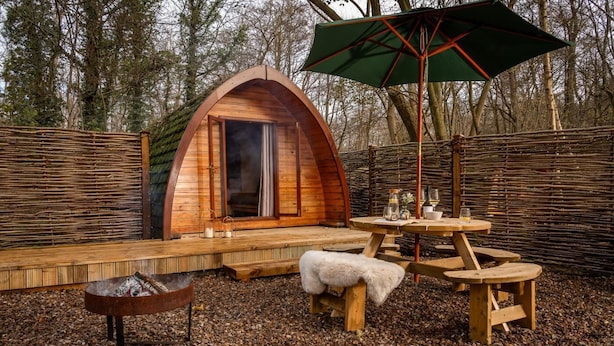 A cozy wooden cabin with a fireplace, a table with chairs, and a large umbrella.