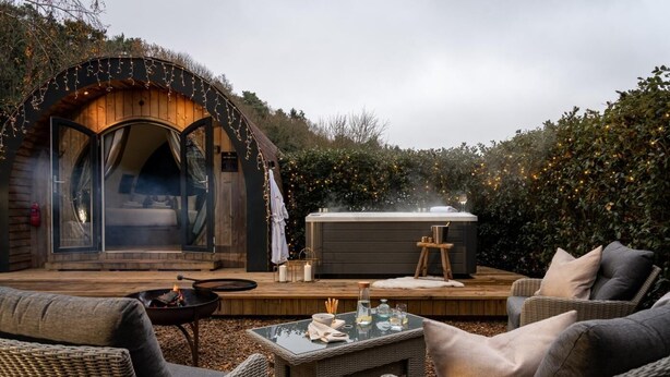 Un espacio exterior acogedor con mobiliario de mimbre, un jacuzzi y una terraza de madera.
