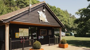 A wooden building with a sloped roof, a reception desk, and a signboard.