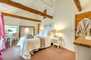 Ein Schlafzimmer mit einem Bett, Nachttischen, einem Bademantel und einer Holzbalkendecke.