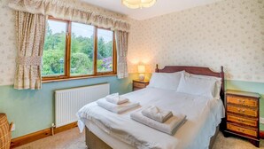 A bedroom with a bed, a window with curtains, a radiator, a bedside table with a lamp, and a nightstand. - 3 Bed in Balmaclellan (oc-i44754) (Balmaclellan)