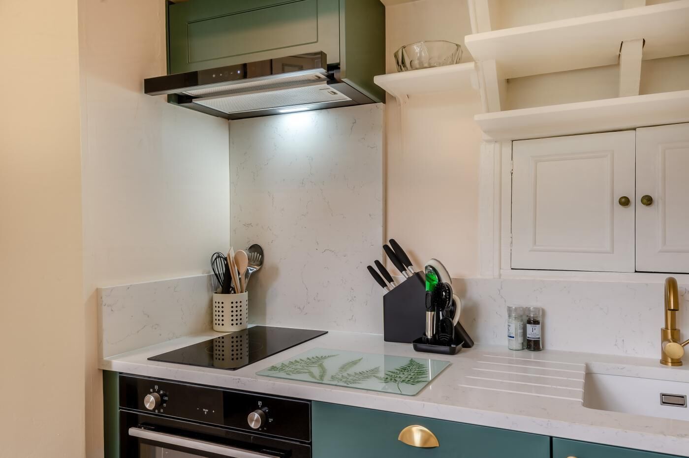 A kitchen with a stove, sink, and cabinets.