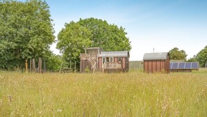 A rustic cabin with a wooden deck and a small shed with solar panels.