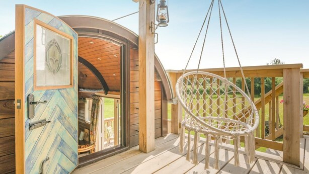 A wooden structure with a hanging chair, a door with a glass panel, and a hanging lantern.