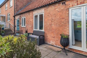 A brick house with a patio, a bench, and a large sliding glass door. - 2 Bed in Laxton (oc-p44858) (Laxton)