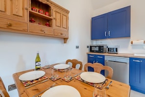 A dining area with a wooden table set for four, a microwave, and a dishwasher in the background. - 2 Bed in Laxton (oc-p44858) (Laxton)