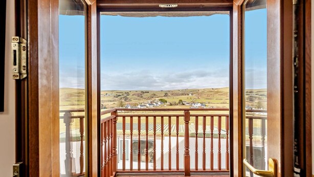 Un balcón de madera con vistas a un paisaje rural.