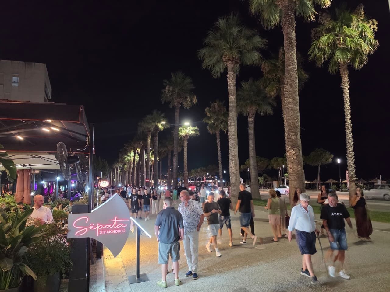 A nighttime outdoor area with a sign for 'Sepata Steak House' and palm trees.