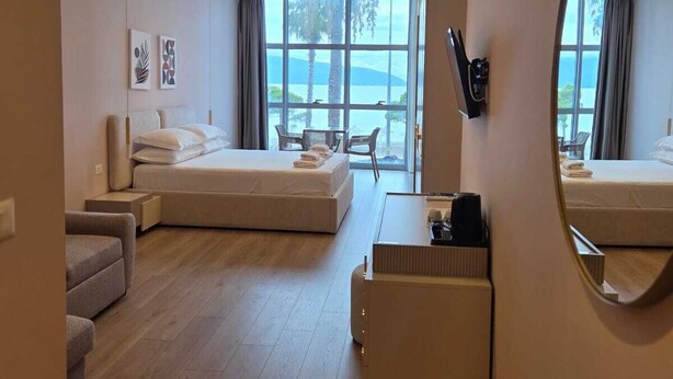 Habitación de hotel moderna con una cama grande, un sofá, un escritorio y vistas al exterior.