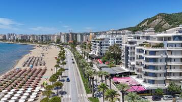A coastal cityscape with a beachfront, multi-story buildings, and a clear sky.