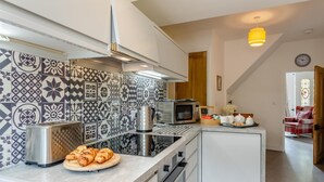 Una cocina moderna con protector contra salpicaduras estampado, electrodomésticos de acero inoxidable y un comedor con una silla de cuadros rojos.