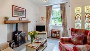 Una sala de estar con chimenea, televisor, sofá y ventana con cortinas.