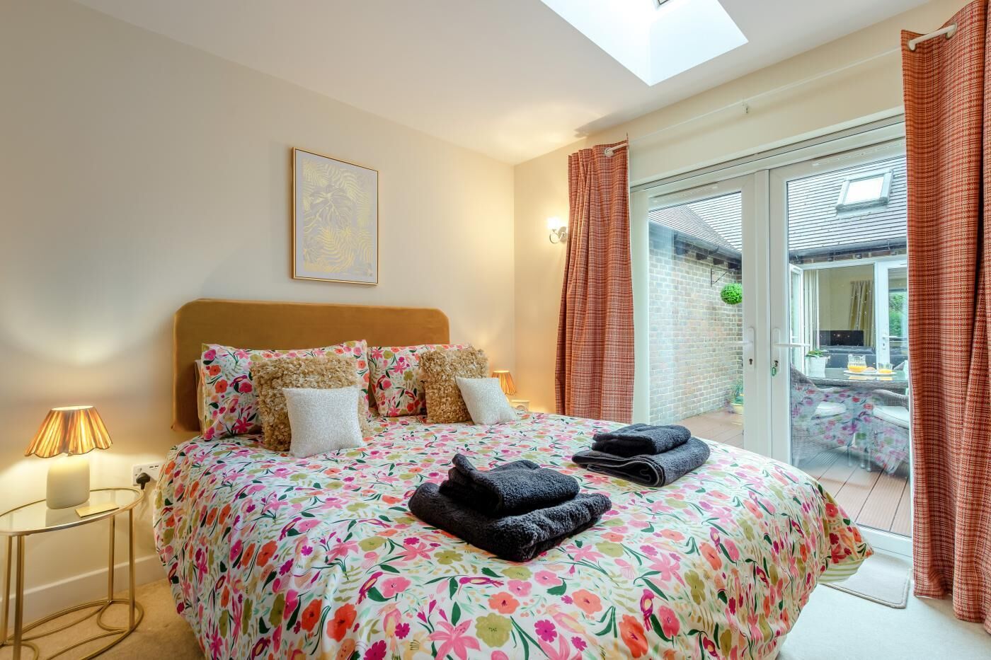 A bedroom with a bed, a bedside lamp, a window with curtains, and a view of the outside.