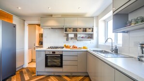 Una cocina moderna con horno empotrado, estufa a gas y un amplio ventanal que proporciona luz natural.