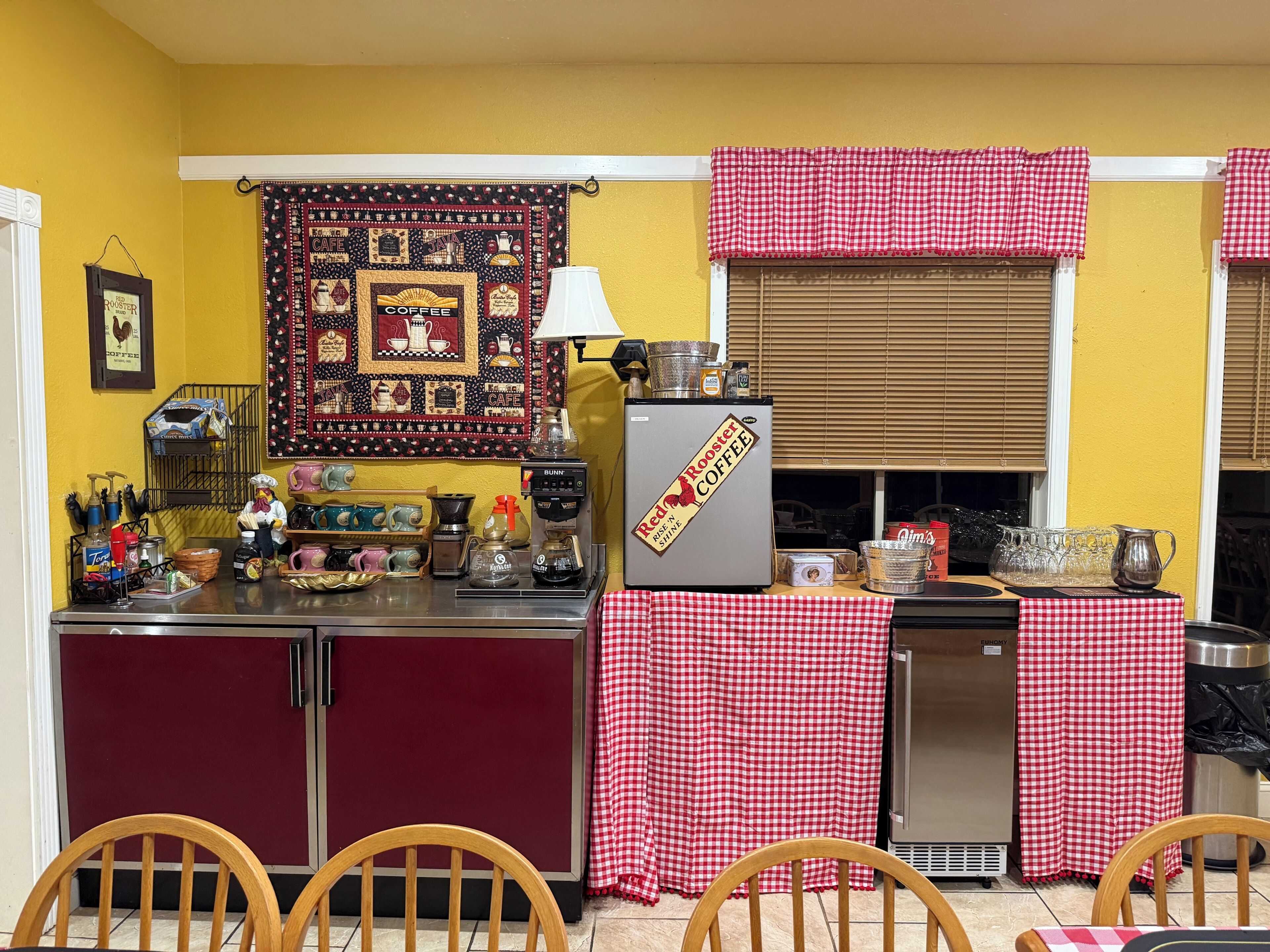Una cocina compacta con refrigerador, cafetera y distintos utensilios de cocina.