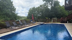 Ein rechteckiger Pool mit Holzterrasse, Liegestühlen und Holzlattenzaun.