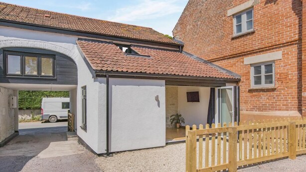 Een gelijkvloers huis met garage, overdekt terras en houten omheining.