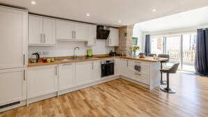 Een moderne keuken met witte kasten, een houten aanrecht en een eethoek met een tafel en stoelen.