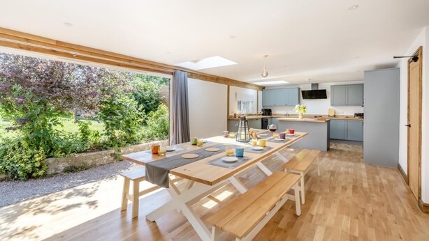 Une cuisine moderne dotée d’un îlot central, de planchers en bois et offrant une vue sur un jardin.