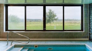 Una piscina amb vistes a un camp verd a través de grans finestres.