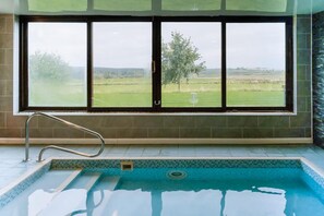 A swimming pool with a view of a grassy field through large windows. - 3 Bed in Berrier (oc-o44951) (Hutton)
