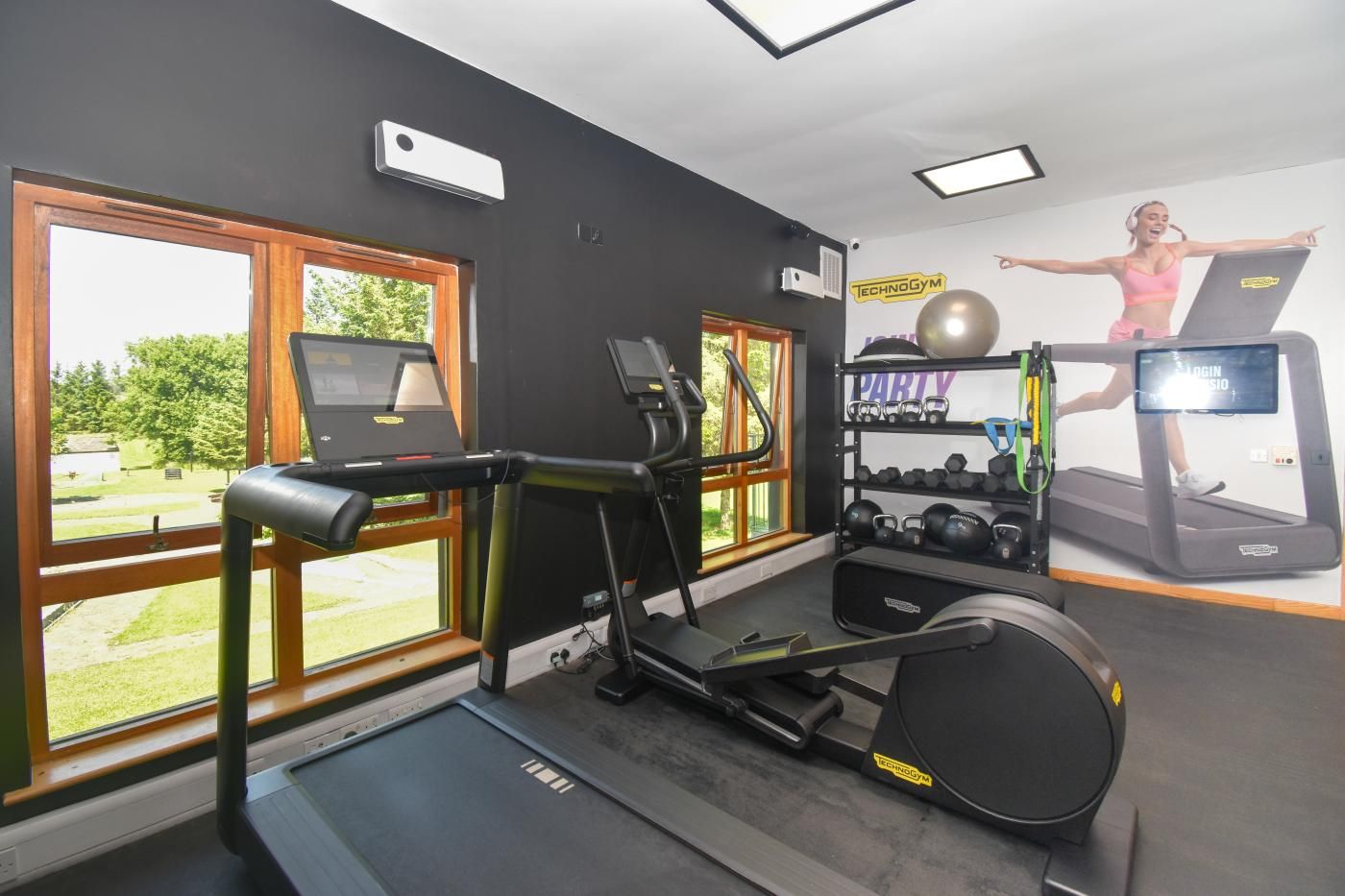 A gym with treadmills, a rowing machine, and a wall with exercise equipment.