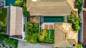 Ein Resort mit Schwimmbad, Liegestühlen und tropischer Bepflanzung.