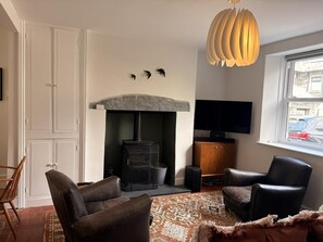 Ein Wohnzimmer mit Kamin, Ledersesseln, einem Fernseher und einem gemusterten Teppich.