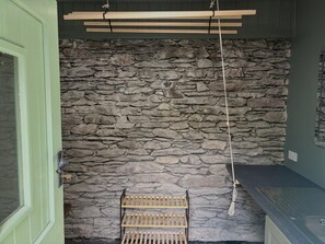 Ein Badezimmer mit Steinwand, Holzregalen und einer grünen Tür.