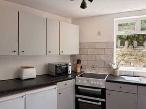 Eine kleine Küche mit weißen Schränken, einem Backofen, einer Mikrowelle und einem Toaster.