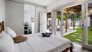 Ein modernes Schlafzimmer mit Bett, Kleiderschrank und Blick auf Pool und Garten.