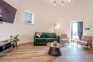 A modern living room with a green sofa, a coffee table, and a TV mounted on the wall. - 4 Bed in Waddington (oc-w42854) (Waddington)