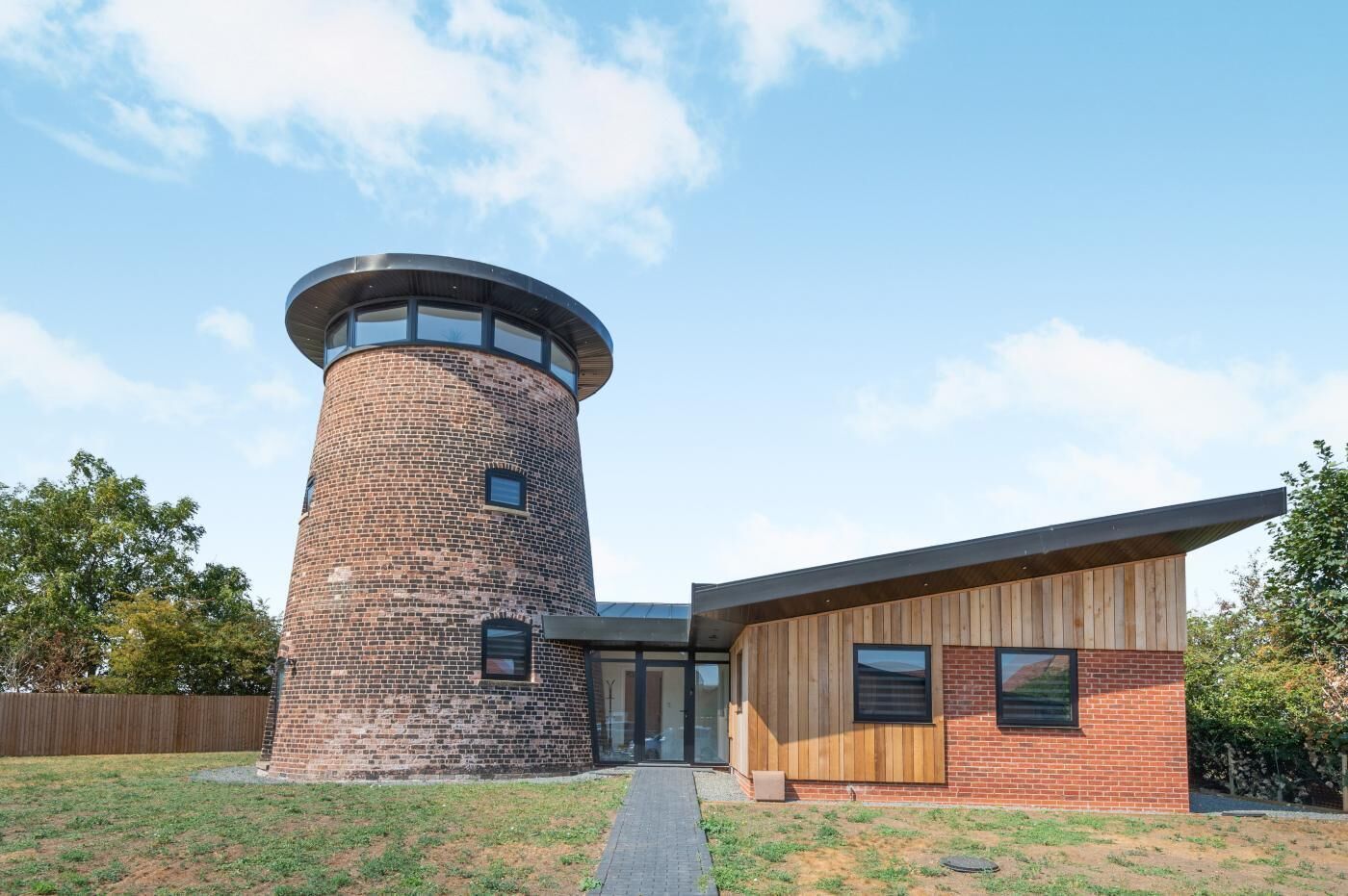 A modern building with a brick tower and a wooden extension.