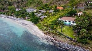 An aerial view of a coastal residential area with houses, a beach, and a clear view of the ocean. - Villa Eden Roc in BANYUNING,  AMED,  ABANG, (BANYUNING,  AMED,  ABANG,)
