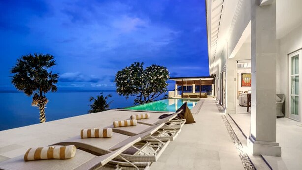 A poolside area with lounge chairs and a view of the ocean at dusk. - Villa Eden Roc in BANYUNING,  AMED,  ABANG, (BANYUNING,  AMED,  ABANG,)