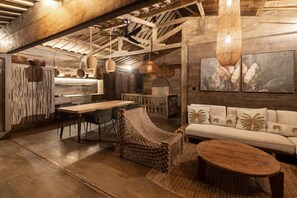 Un interior rústico con vigas de madera a la vista, un comedor, un sofá y una lámpara colgante.