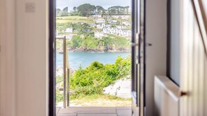 A view through an open door to a coastal town with buildings and greenery. - 4 Bed in Polruan (oc-s41411) (Fowey)