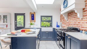 A modern kitchen with a skylight, a brick accent wall, and a central island. - 4 Bed in Polruan (oc-s41411) (Fowey)