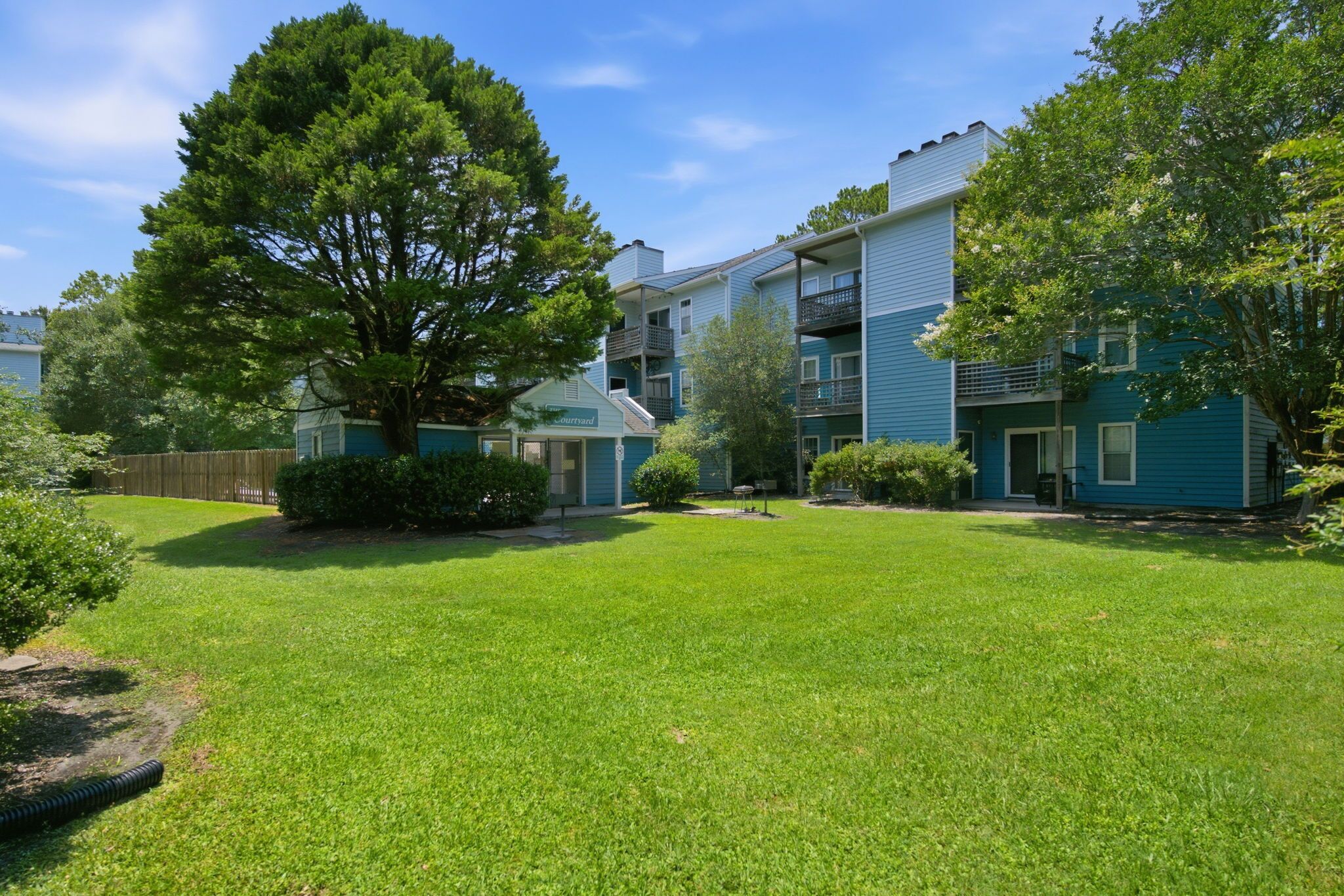 A residential building with a well-maintained lawn, a large tree, and a small sign indicating a garage.