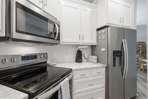 A modern kitchen with white cabinets, stainless steel appliances, and a built-in microwave. - Coastal Condo: Pet friendly/Pool/Mins to UNCW, Downtown & Wrightsville Beach (Wilmington)