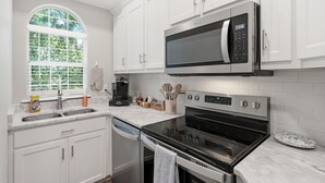 A modern kitchen with white cabinetry, a built-in microwave, a stove, and a dishwasher. - Coastal Condo: Pet friendly/Pool/Mins to UNCW, Downtown & Wrightsville Beach (Wilmington)