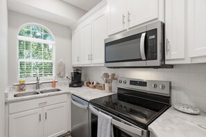 A modern kitchen with white cabinetry, a built-in microwave, a stove, and a dishwasher. - Coastal Condo: Pet friendly/Pool/Mins to UNCW, Downtown & Wrightsville Beach (Wilmington)