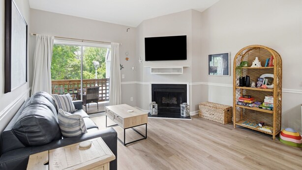 A living room with a sofa, coffee table, fireplace, TV, and bookshelf. - Coastal Condo: Pet friendly/Pool/Mins to UNCW, Downtown & Wrightsville Beach (Wilmington)