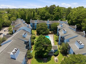 A residential complex with multiple two-story buildings, a central swimming pool, and surrounding greenery. - Coastal Condo: Pet friendly/Pool/Mins to UNCW, Downtown & Wrightsville Beach (Wilmington)